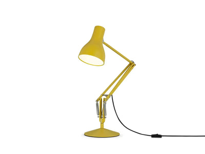 Żółta lampa biurkowa typu anglepoise na białym tle, idealna do home office