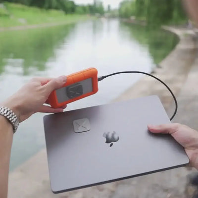 Zewnętrzny dysk twardy podłączony do laptopa nad wodą, mobilna praca na zewnątrz