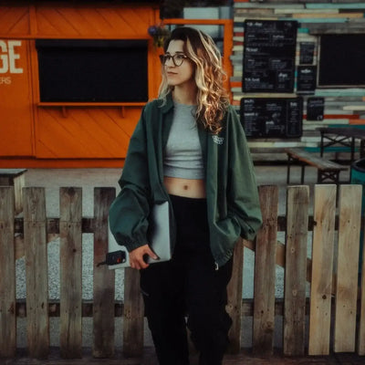 Kobieta z laptopem i akcesoriami biurowymi przy drewnianym płocie, nowoczesny desk setup na zewnątrz